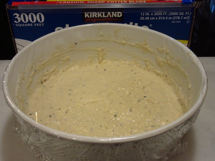 Plastic wrap covering a bowl of Everything English Muffin Bread dough for proofing.