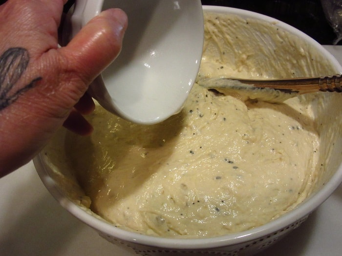 Baking soda and water being added to a bowl of dough.