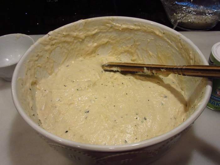 A wooden spoon mixing a bowl of dough.