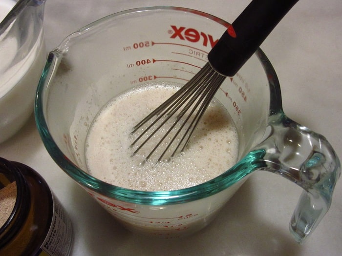 A whisk in a glass measuring cup.