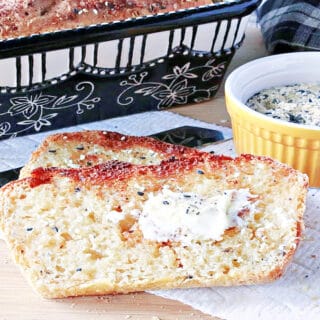 A couple of slices of toasted Everything English Muffin Bread with butter and a dish of everything seasoning on the side.