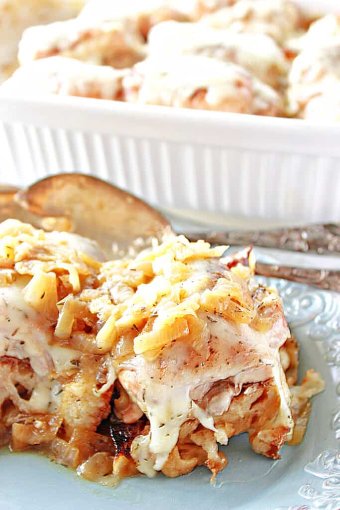 A vertical closeup of some French Onion Chicken Thighs on a blue platter with serving utensils.