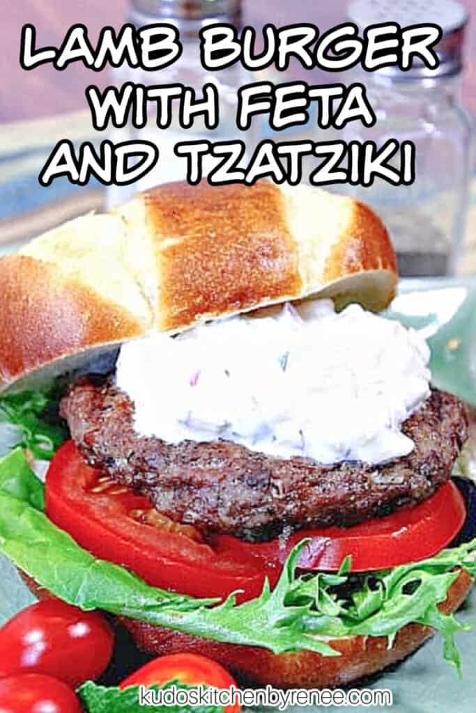 A closeup vertical image of a Lamb Burgers with Feta and Tzatziki along with a title text overlay graphic with some tomato and lettuce.