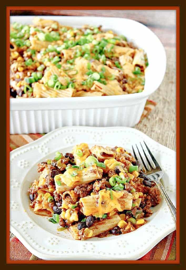 A vertical photo of a plate filled with Mexican Mac and Cheese Casserole in the foreground and a baking dish filled with it in the background.