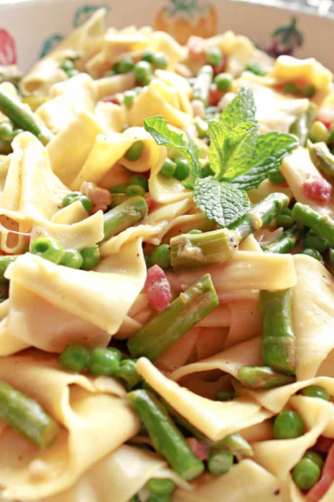 An extreme vertical closeup of some Pappardelle with Spring Vegetables pasta with peas, asparagus, fresh mint and pancetta.