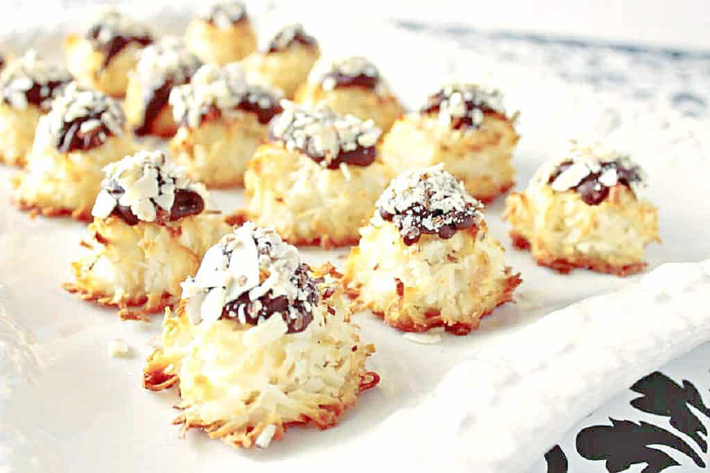 A white platter filled with Almond Joy Coconut Macaroons with chocolate tops and chopped nuts.