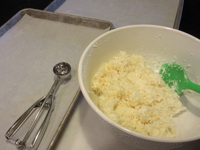 A cookie scoop and coconut macaroon dough in a bowl