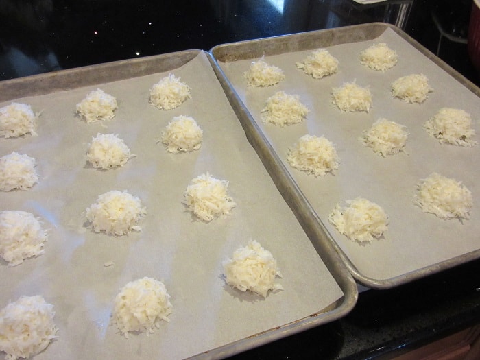 scoops of coconut macaroon cookies on parchment lined baking sheets.