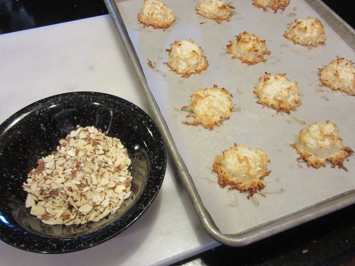 Toasted almonds in a bowl next to baked coconut macaroons.
