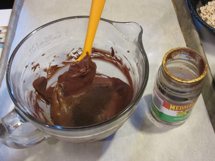 Melted chocolate in a glass bowl with espresso powder.