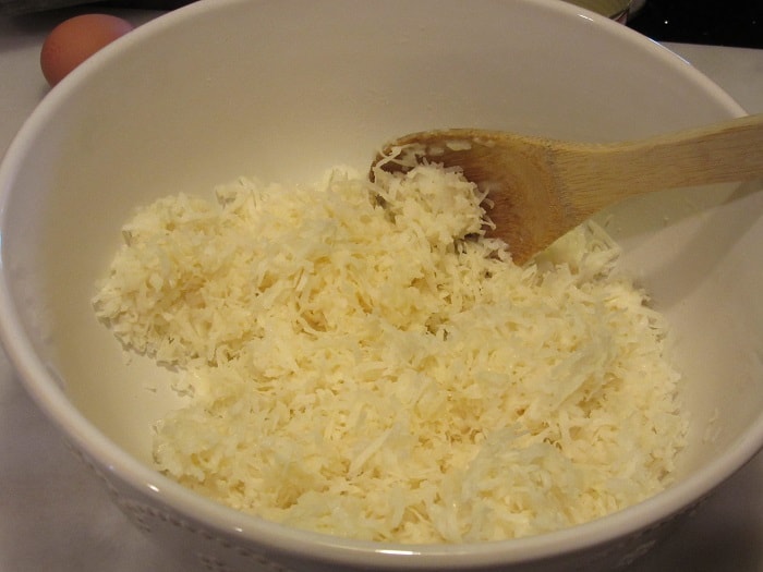 A wooden spoon in a bowl with coconut.