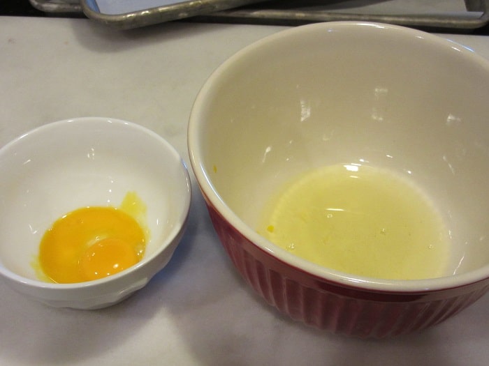 Egg yolks and egg whites in two separate bowls.