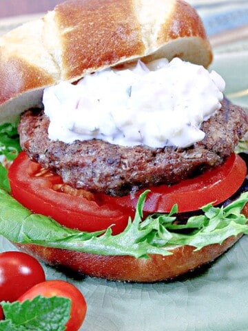 A Lamb Burger with lettuce and tomato on a green plate.