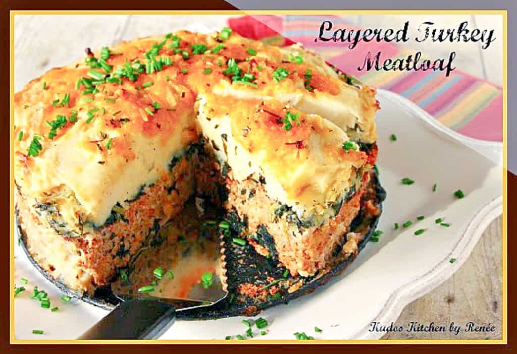 A horizontal photo of a Layered Turkey Meatloaf on a square platter with a serving spatula.