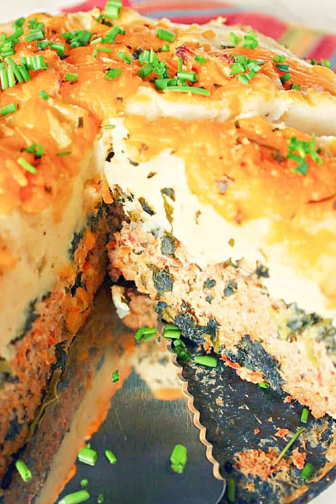 A vertical closeup photo of a Layered Turkey Meatloaf with mashed potatoes and melted cheese on top.