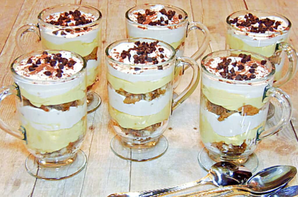 A horizontal photo of six Skinny Tiramisu Parfaits in glass Irish coffee mugs with spoons and chocolate chips.