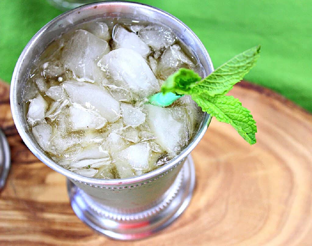 A horizontal photo of the inside of a metal glass cocktail glass filled with a Traditional Mint Julep with crushed ice and fresh mint.