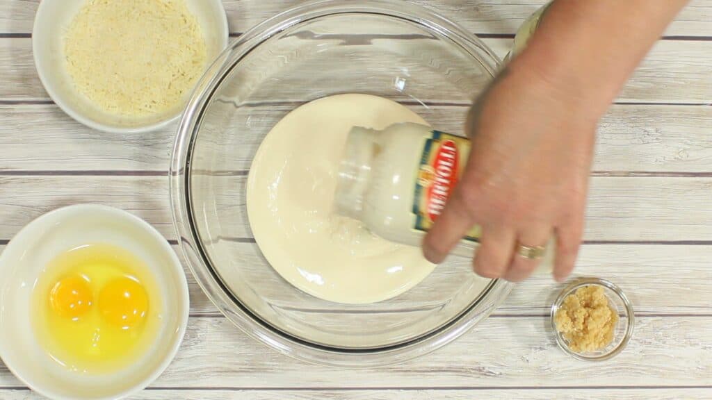 A jar of alfredo sauce being added to a bowl.