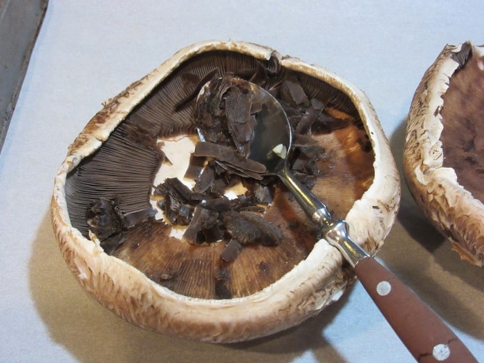 Using a spoon to remove the gills from a mushroom.