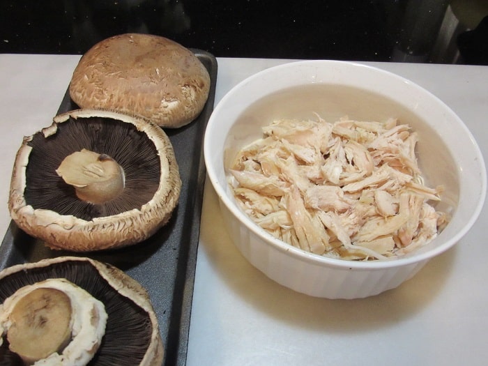 Portobello mushroom caps and shredded chicken in a bowl.