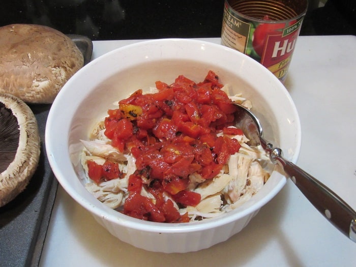 Roasted tomatoes in a bowl with shredded chicken.
