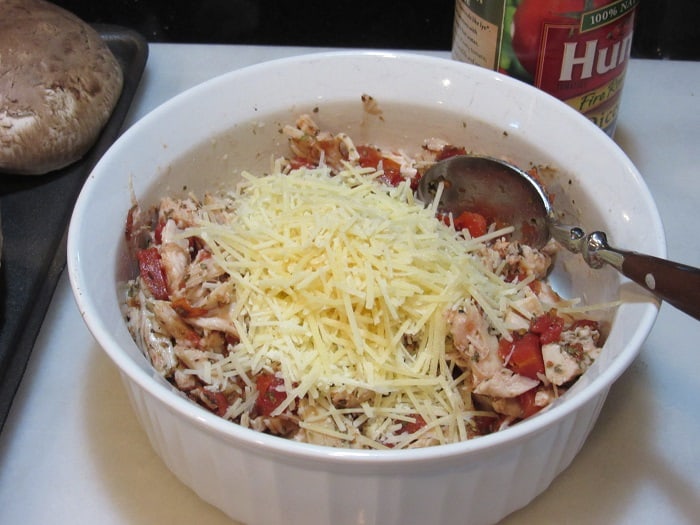 Shredded Parmesan cheese in a bowl with chicken and tomatoes.