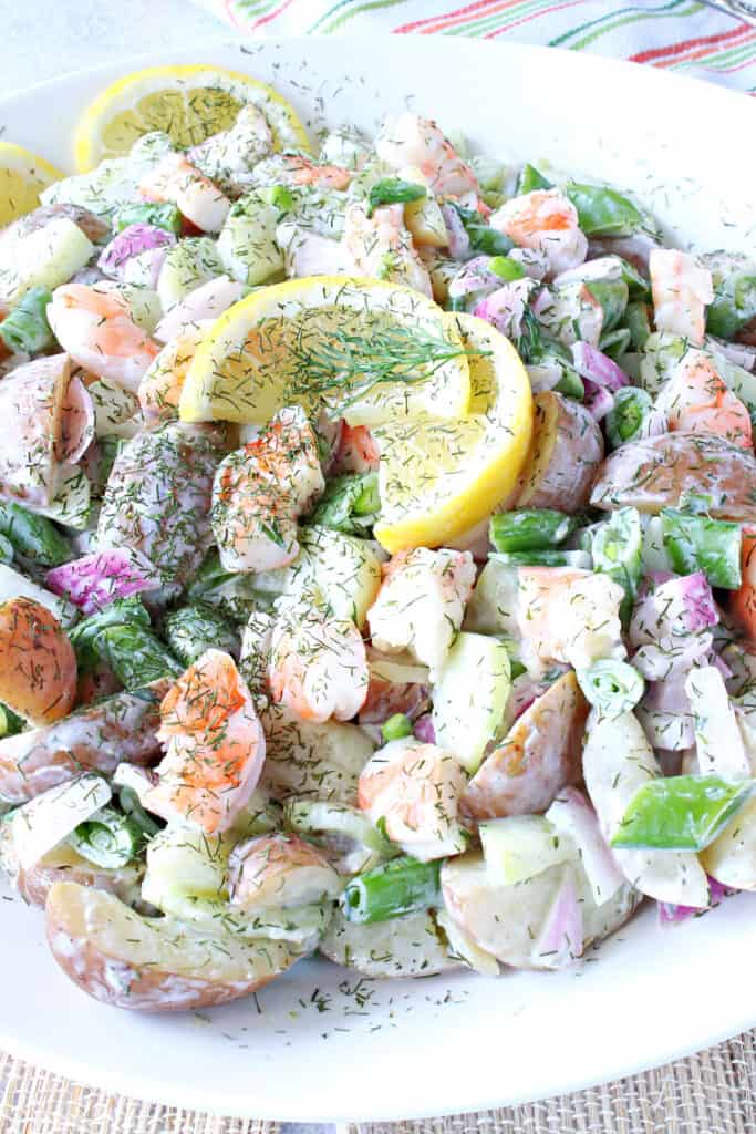 A closeup vertical image of some Dilled Cucumber Salad with Shrimp in a white bowl with dill as garnish.