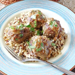 Four Pork Meatballs with Apples and Onion on a plate with rice.
