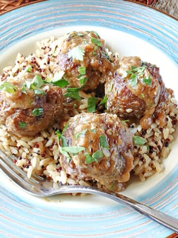 Four Pork Meatballs with Apples and Onion on a plate with rice.