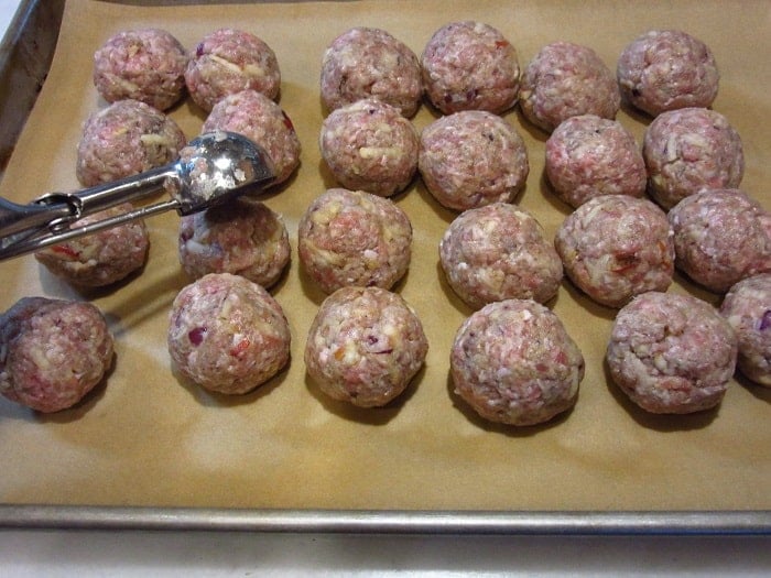 Uncooked meatballs with a scoop.