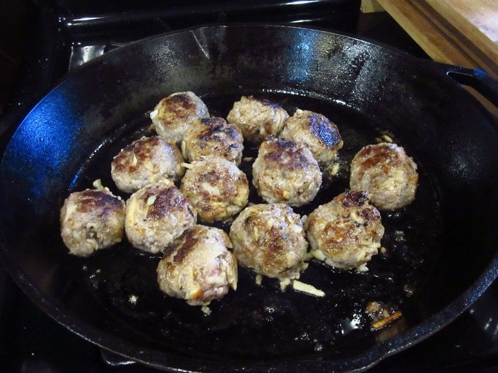 Browned pork meatballs in a cast iron skillet.
