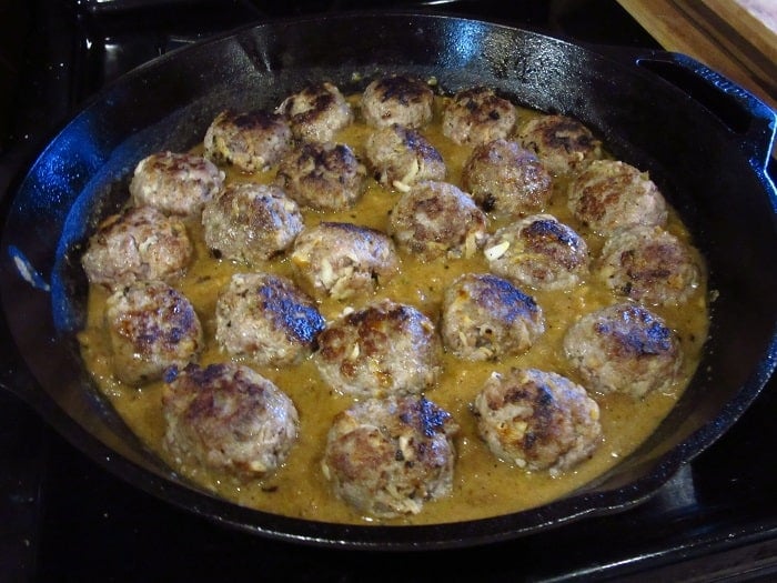 Pork meatballs in a cast iron skillet with sauce.+