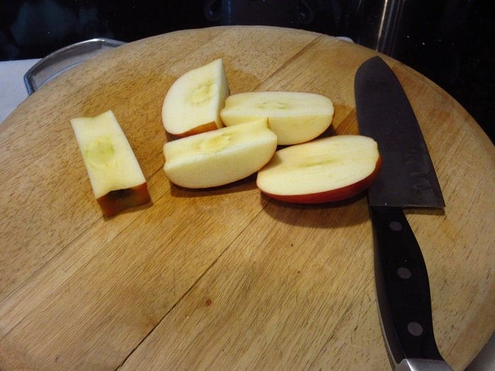 Apples on a cutting board with a knife.