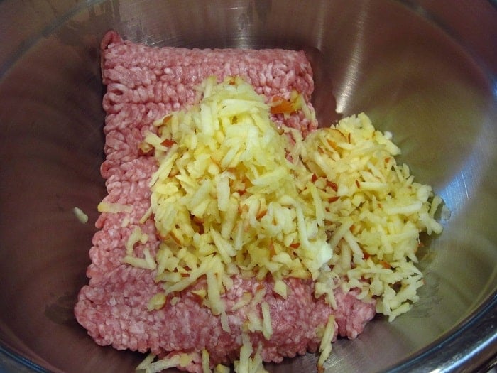 Ground pork and grated apples in a bowl.