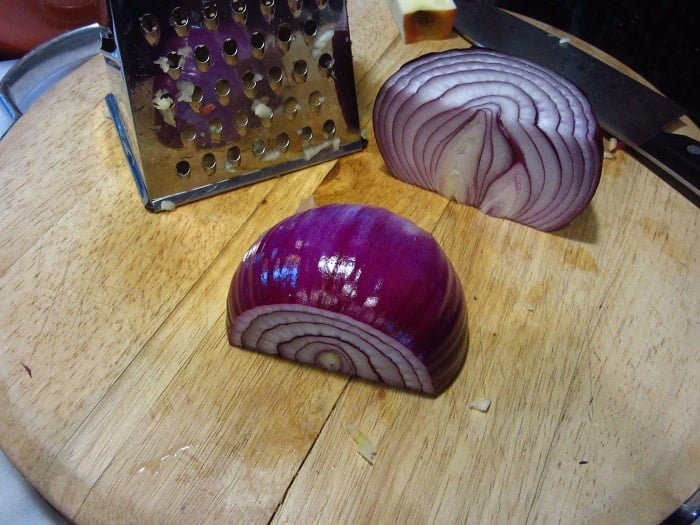 A halved red onion on a cutting board.
