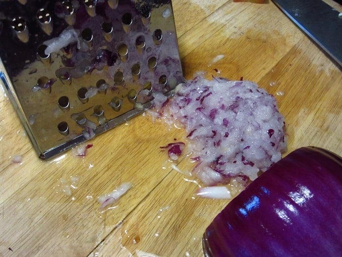 A grated red onion on a cutting board.