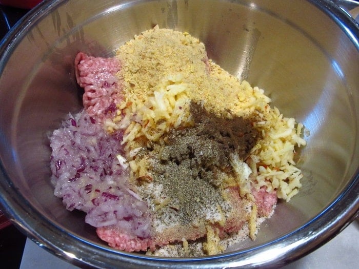 Ground pork, grated apple and onion in a bowl with seasonings.