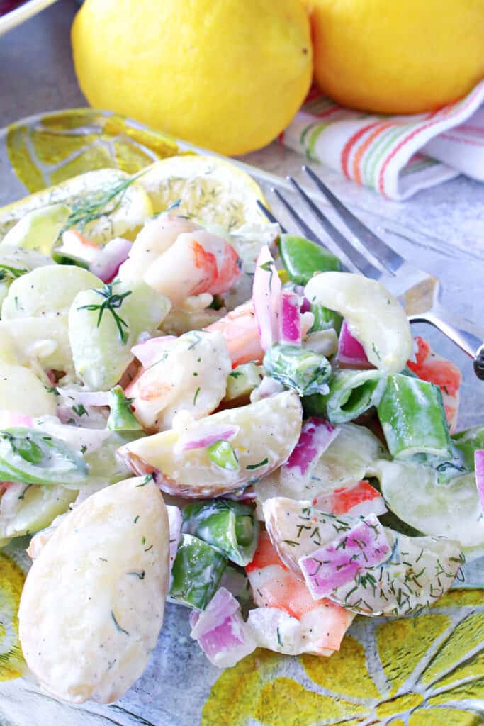A Cucumber and Shrimp Salad on a glass plate with lemons and a fork.