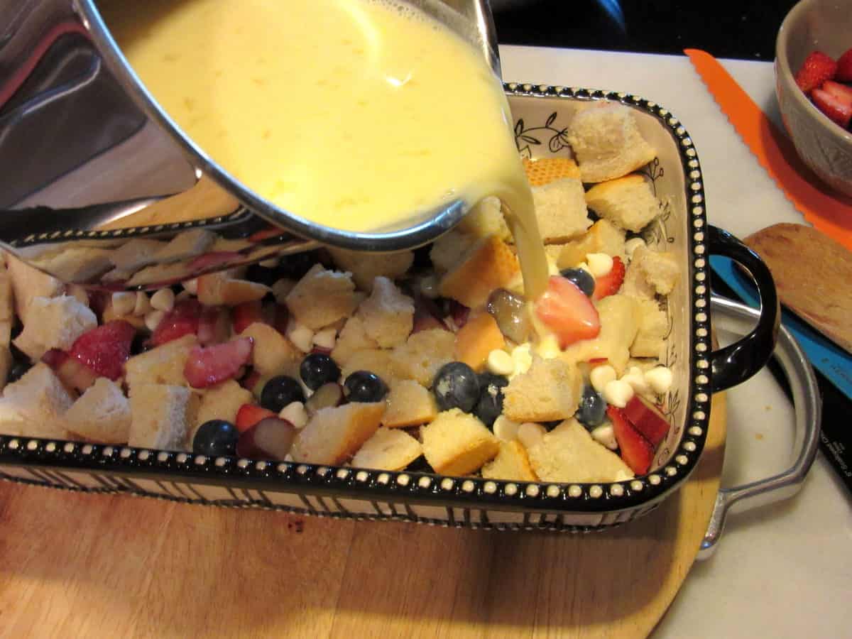 Egg custard being poured over a red, white, and blue bread pudding.
