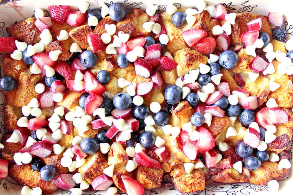 A direct overhead photo of Red, White, and Blue Bread Pudding with brown bread, strawberries, rhubarb, and white chocolate.