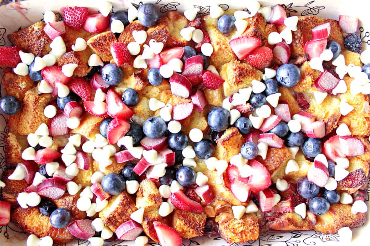 White chocolate, rhubarb, strawberries and blueberries on top of a baked bread pudding.