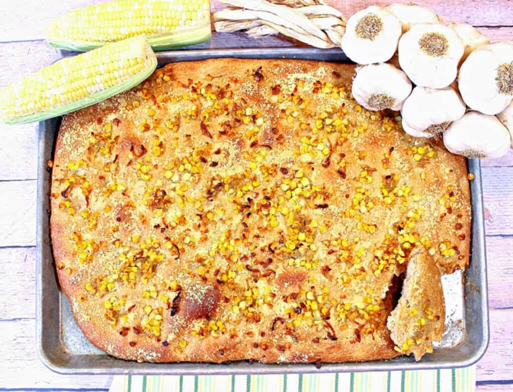 A overhead horizontal photo of an entire Garlic Focaccia with Sweet Corn on a sheet tray.