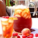 A pitcher and a glass of Peach and Raspberry Sun Tea outside with ice.