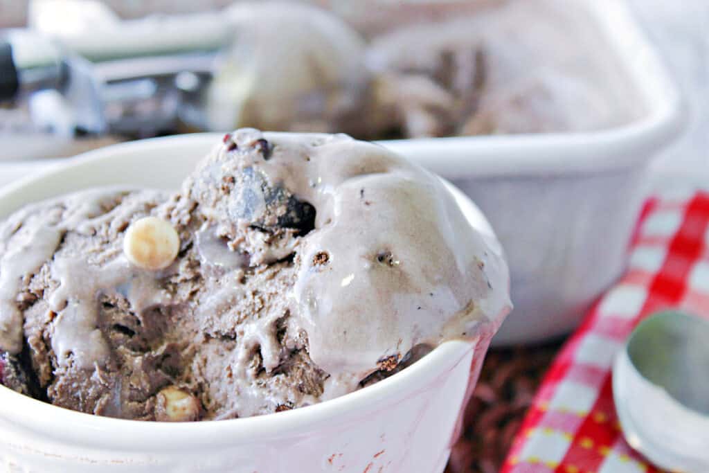 A closeup image of a semi-melted dish of Chocolate Cherry Kahlua Ice Cream with white and semi-sweet chocolate chips.