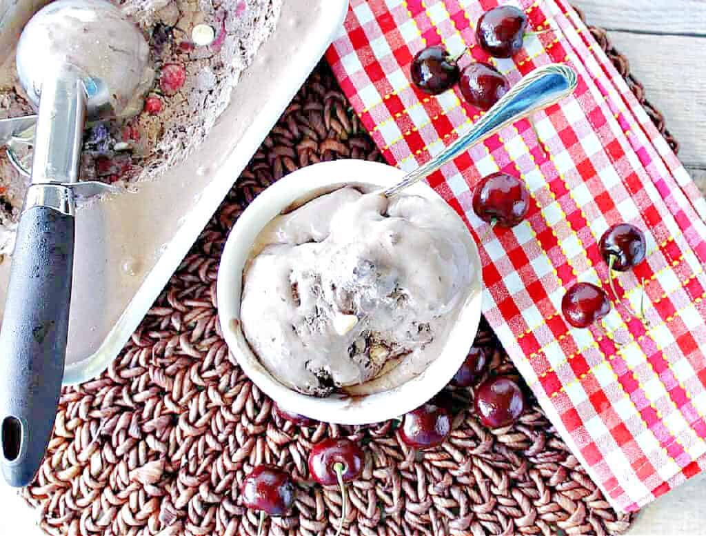 An direct overhead photo of a small dish of Chocolate Cherry Kahlua Ice Cream along with a loaf pan filled with the same ice cream in the background.