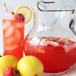 A glass and a pitcher filled with Lite Pink Lemonade with Strawberry Simple Syrup.