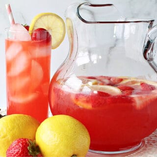 A glass and a pitcher filled with Lite Pink Lemonade with Strawberry Simple Syrup.