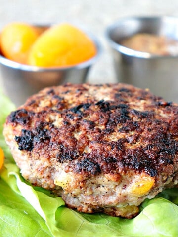 A browned Pork Burger with Dried Apricots on a lettuce leaf.