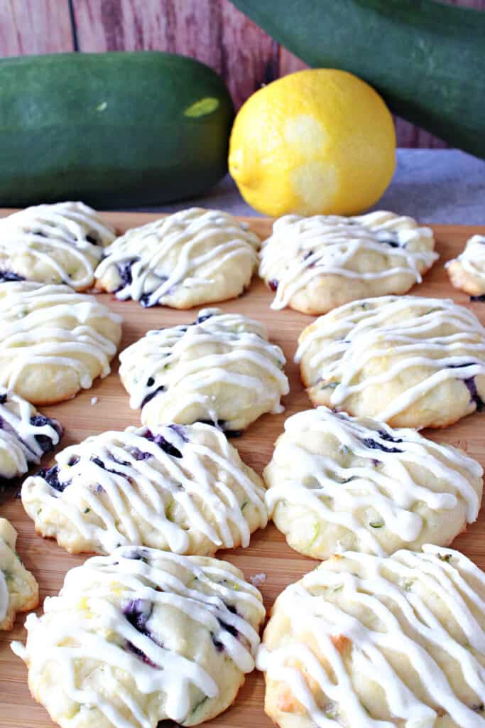 A closeup vertical photo of Zucchini Ricotta Cookies in the foreground along with a zucchini and lemon in the background.