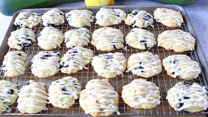 A baking sheet filled with Zucchini Ricotta Cookies that are drizzled with icing.